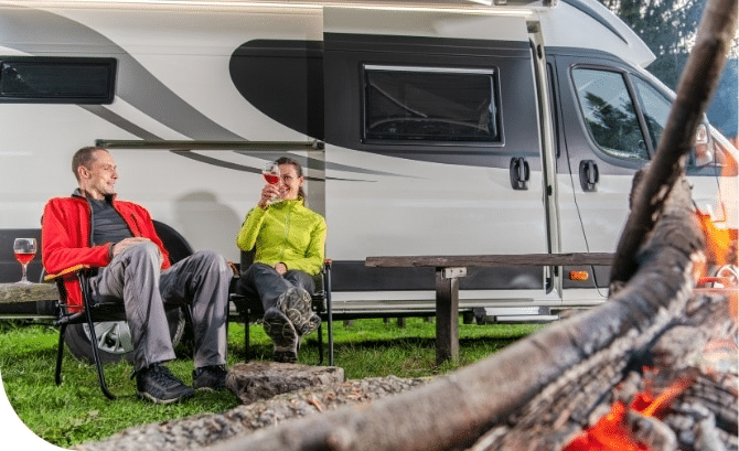 men and women drink besides a campervan
